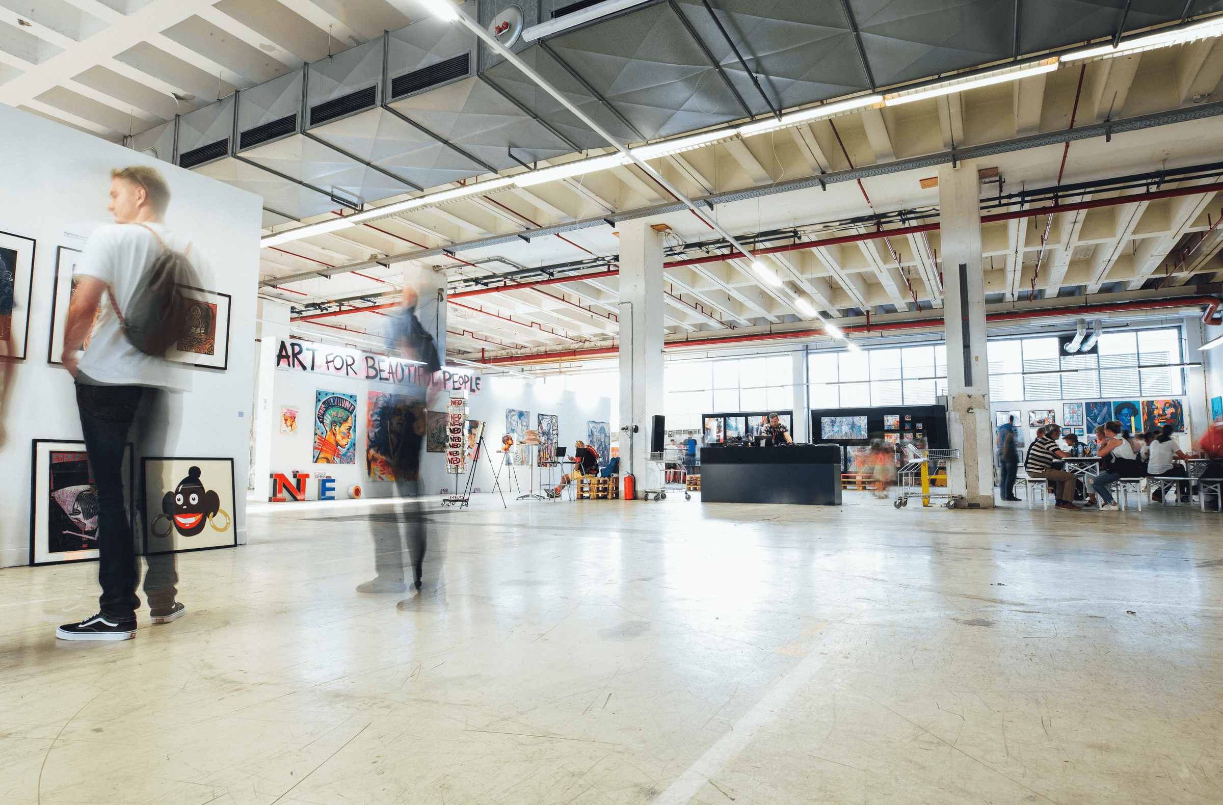 Visitors walking through an art fair in a converted industrial hall
