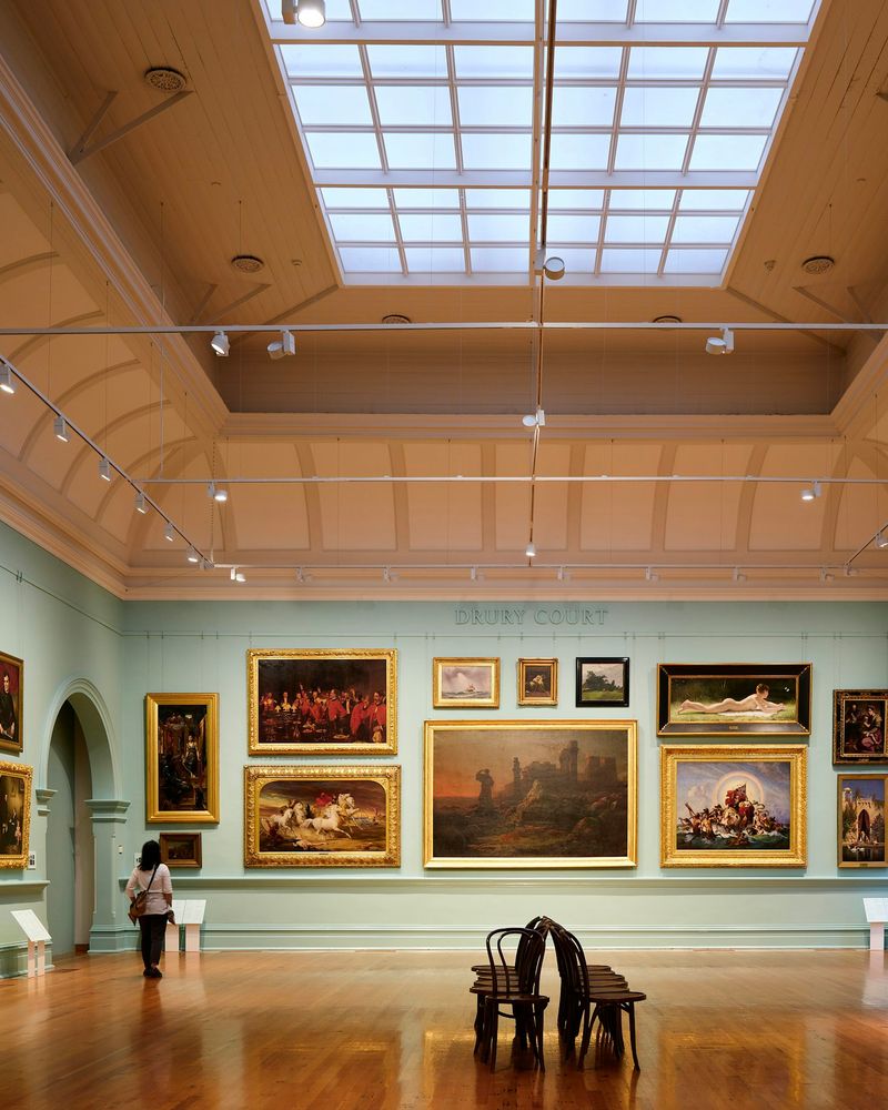 A museum gallery lit by a skylight, hung floor to ceiling